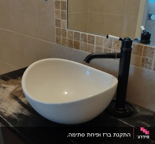 כיור עגול עם ברז שחור על משטח כהה